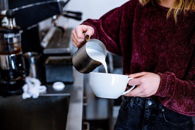 Barista-pouring-hot-milk-into-coffee