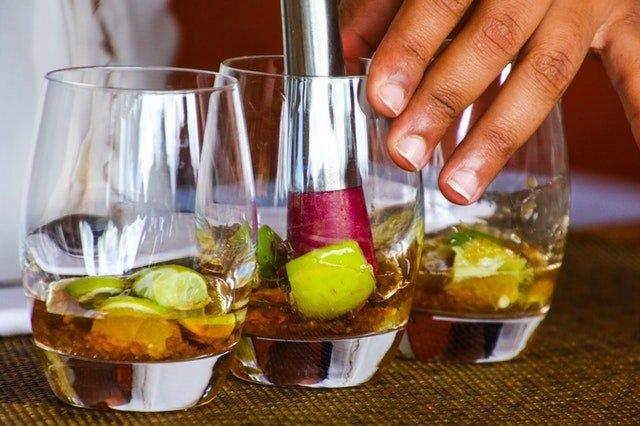 Bartender-muddling-limes-and-rum-in-glass-tumblers
