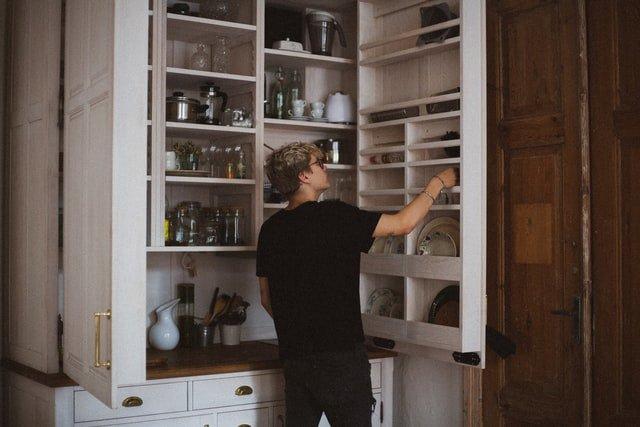 Person-looking-inside-a-tall-kitchen-cupboard