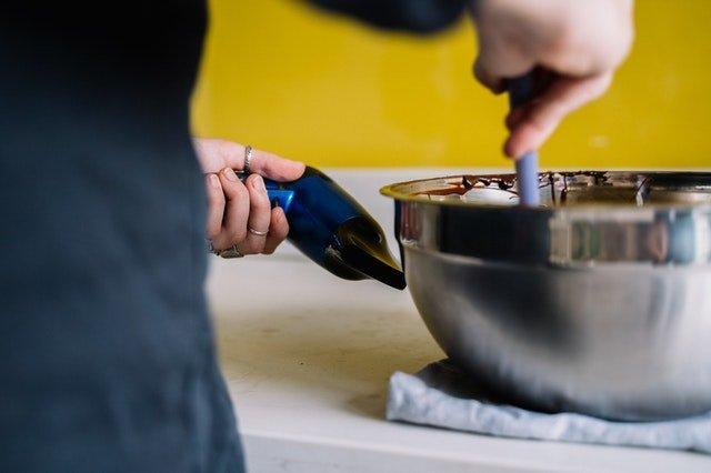 Person-measuring-the-temperature-of-melted-chocolate-in-a-silver-bowl