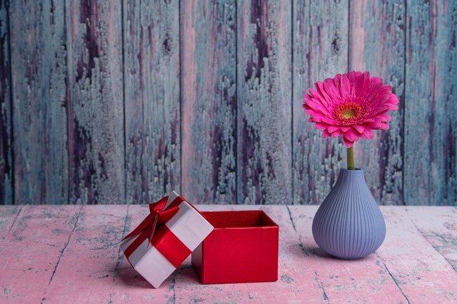 Red-gift-box-and-pink-flower-in-a-blue-vase