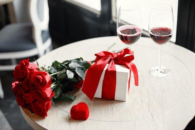 Red-roses-beside-a-gift-box-and-two-glasses-of-red-wine