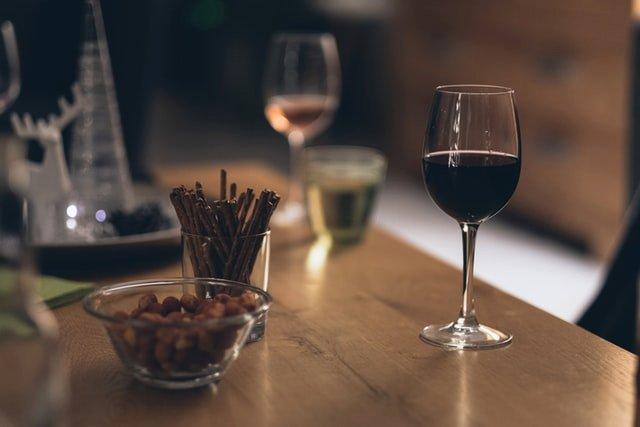Wine-glasses-on-a-table-next-to-a-jar-of-pretzel-sticks-and-nuts